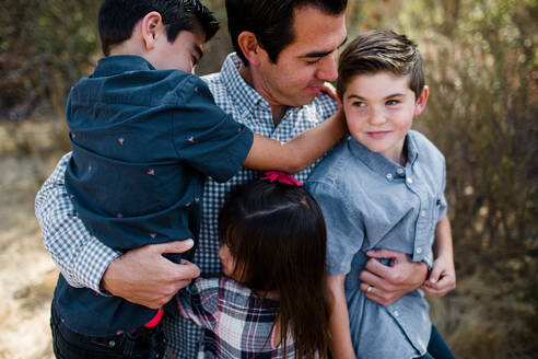Vater hält drei Kinder auf einem Feld in San Diego - CAVF94117