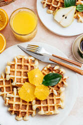 Hausgemachte Waffeln auf einem hellrosa Hintergrund. Orangensaft. Obst - CAVF94122