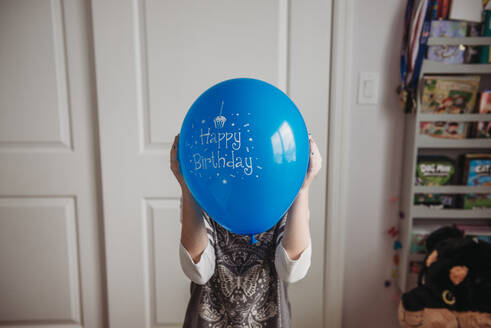 Tween Mädchen hält blauen Geburtstagsballon vor dem Gesicht - CAVF94149