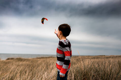Junge zeigt auf Kite-Surfer in den Wolken an einem Strand im Michigansee - CAVF94156
