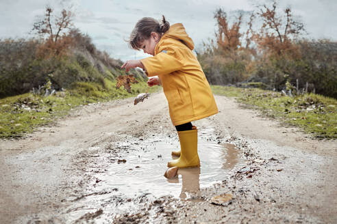 Ein 2-jähriges Mädchen spielt mit einer Schlammpfütze - CAVF94175