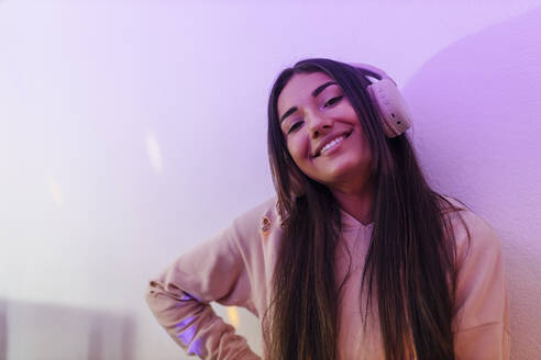 Lächelnde junge Sängerin hört Musik über Kopfhörer im Studio - JRVF01018