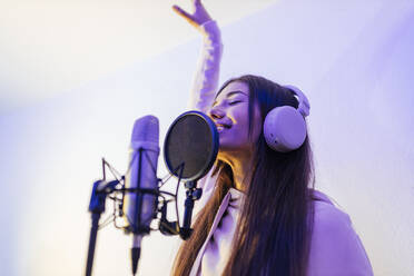 Female singer with hand raised singing at studio - JRVF01025