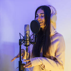 Sängerin mit geschlossenen Augen, die gestikuliert, während sie durch ein Mikrofon im Studio singt - JRVF01027