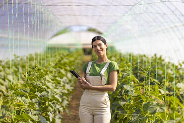 Selbstbewusste Landwirtin mit digitalem Tablet im Gewächshaus stehend - OIPF01006