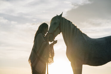 Young woman with horse during sunset - DAMF00801