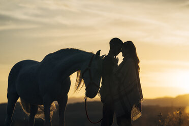 Romantisches junges Paar mit Pferd bei Sonnenuntergang - DAMF00810