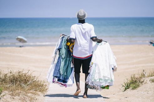 Verkäufer mit Kleidern zu verkaufen zu Fuß auf der Promenade am Strand - OCMF02139