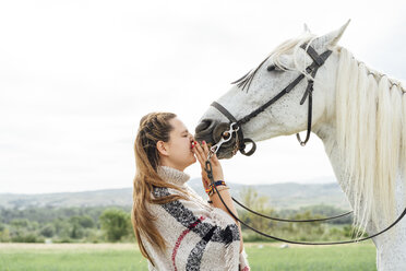 Young woman standing with white horse at countryside - DAMF00812