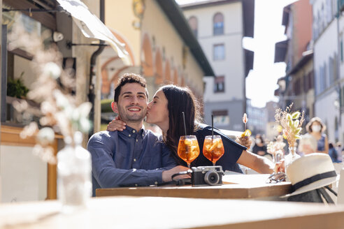 Junge Frau küsst Mann in einem Straßencafé an einem sonnigen Tag - EIF01187