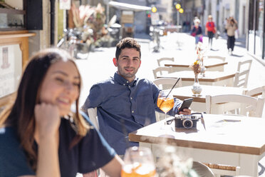 Männlicher Tourist mit Mobiltelefon, der an einem sonnigen Tag eine Frau ansieht - EIF01199