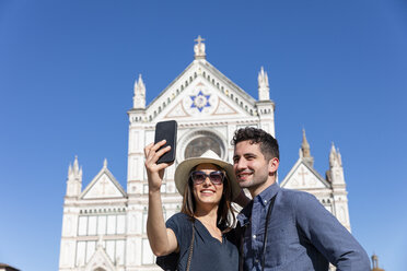 Tourist couple taking selfie through smart phone in front of Basilica Of Santa Croce, Florence, Italy - EIF01206
