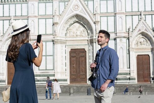 Weiblicher Tourist fotografiert Mann durch Smartphone auf der Piazza Di Santa Croce, Florenz, Italien - EIF01212