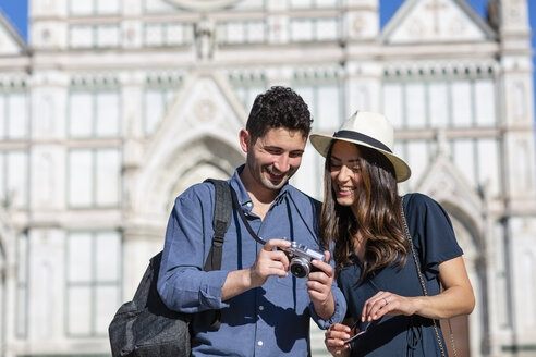 Lächelnde Touristen beim Überprüfen der Kamera mit der Basilika Santa Croce im Hintergrund in Florenz, Italien - EIF01215