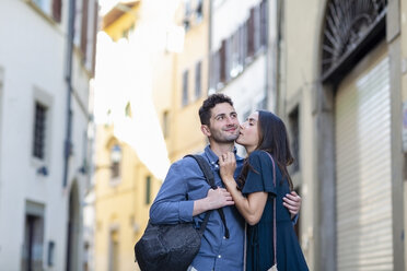 Female tourist kissing man while standing on city street - EIF01225