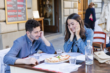 Paar lächelt bei der Betrachtung einer Pizza auf dem Tisch - EIF01247