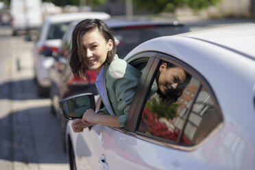 Businesswoman leaning outside car window during sunny day - JSMF02310