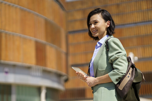 Smiling female professional looking away while holding digital tablet - JSMF02318