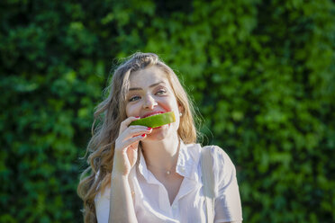 Junge Frau isst Wassermelone im Garten an einem sonnigen Tag - EIF01285