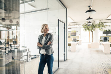 Confident businesswoman with arms crossed standing at office door - JOSEF04788