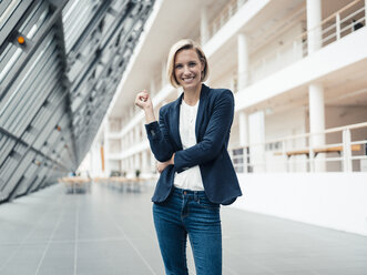 Smiling businesswoman standing at office lobby - JOSEF04795