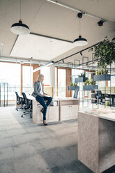 Female entrepreneur using digital tablet while sitting on desk - JOSEF04801