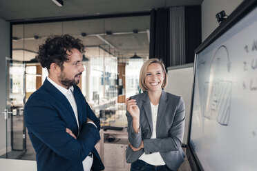 Male entrepreneur standing with arms crossed by colleague in office - JOSEF04816