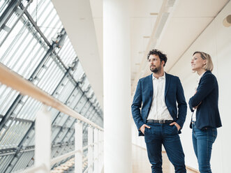 Nachdenkliche Geschäftspartner, die wegschauen, während sie im Büro stehen - JOSEF04832