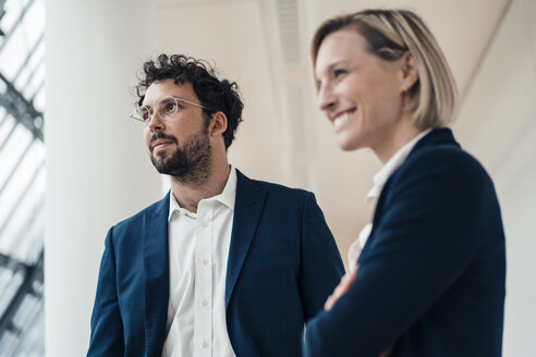 Nachdenklicher männlicher Unternehmer, der wegschaut, während er neben einem Kollegen im Büro steht - JOSEF04860