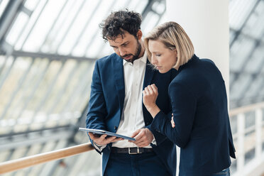 Businessman using digital tablet while standing by colleague in office - JOSEF04867