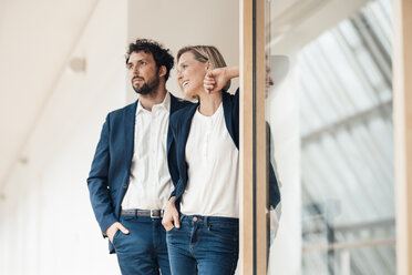 Lächelnde Geschäftspartner, die mit der Hand in der Tasche im Büro stehen - JOSEF04875