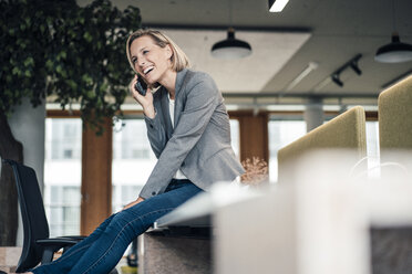 Smiling businesswoman talking on mobile phone at office - JOSEF04902