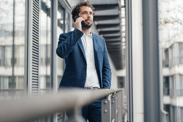 Geschäftsmann, der am Fenster mit seinem Mobiltelefon spricht - JOSEF04924