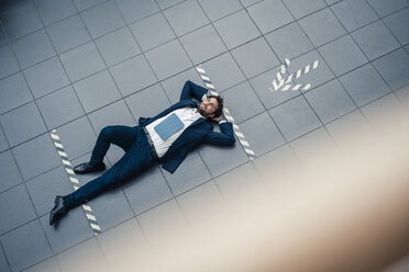 Businessman with digital tablet looking away while lying on office floor - JOSEF04928