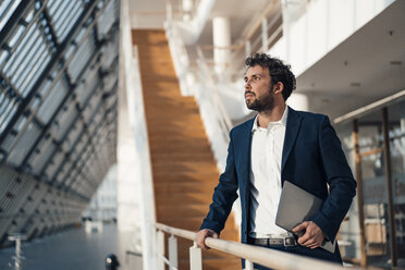 Male entrepreneur with laptop looking away while standing by railing - JOSEF04931