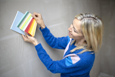 Lächelnde Bauunternehmerin bei der Auswahl der Farbe an der Wand auf der Baustelle - HMEF01293