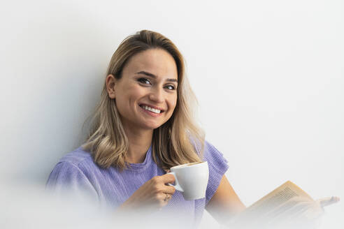 Schöne Frau mit Buch lächelnd bei einem Kaffee im Cafe - PNAF01988