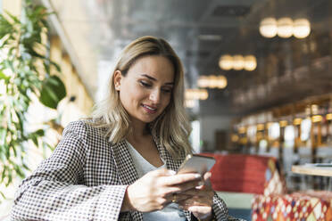 Schöne weibliche Freiberuflerin Text-Messaging beim Sitzen im Café - PNAF02000