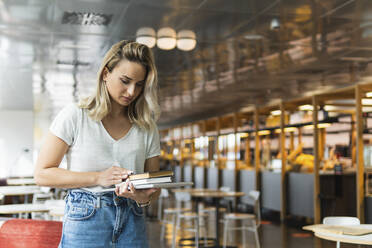 Female professional holding diaries and digital tablet at cafe - PNAF02006