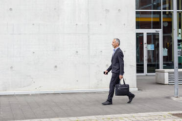 Male business professional with briefcase walking near office building - EIF01309