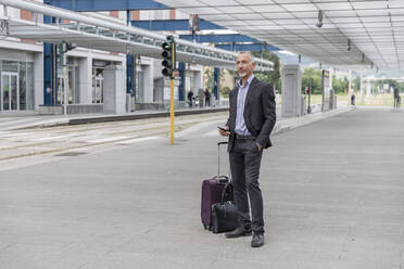 Businessman with luggage waiting for train at railroad station - EIF01317