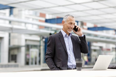 Businessman talking on smart phone at railroad station - EIF01327