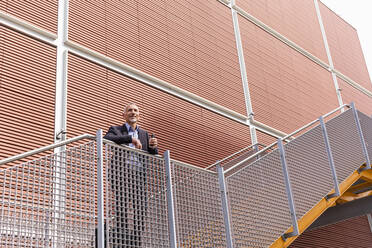 Geschäftsmann lehnt sich an ein Treppengeländer in der Nähe eines Gebäudes - EIF01346