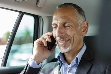 Businessman talking on smart phone in car - EIF01362