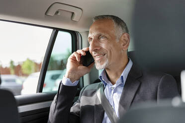 Male professional talking on mobile phone while sitting in car - EIF01363