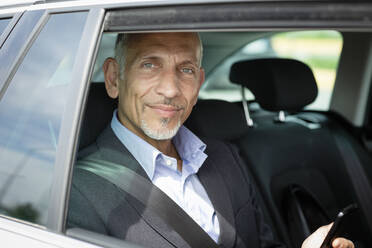 Smiling businessman sitting on back seat in car - EIF01375