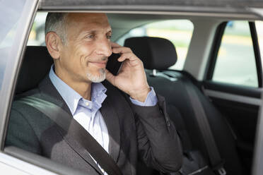 Smiling male professional talking on mobile phone in car - EIF01376
