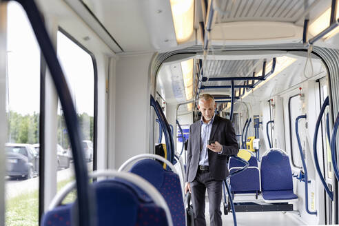 Männlicher Berufstätiger mit Smartphone in der Straßenbahn - EIF01387