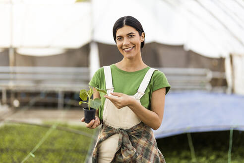 Smiling female farm worker standing with potted plant - OIPF01083