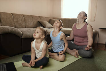Son and daughter practicing yoga with mother at home - ZEDF04235